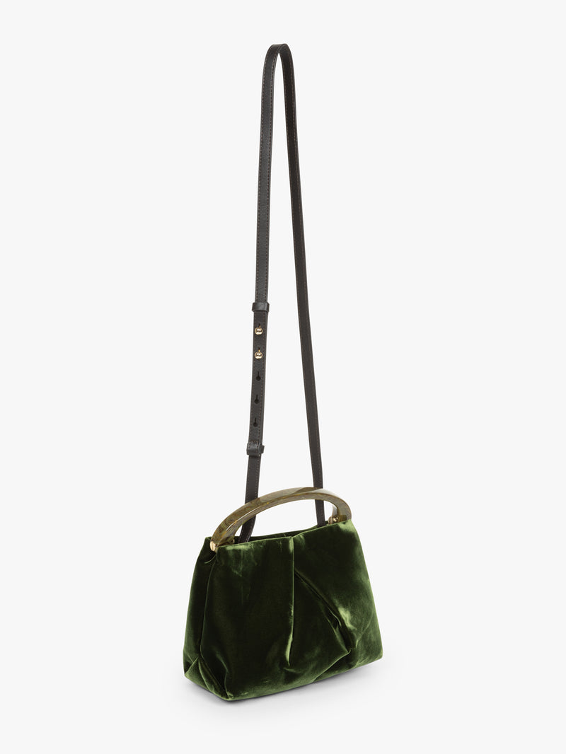 Green velvet handbag with a strap on a white background