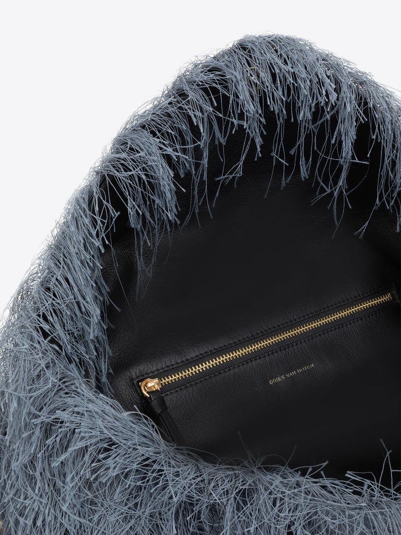 Close-up of a handbag with a gold zipper, featuring a textured blue hood.