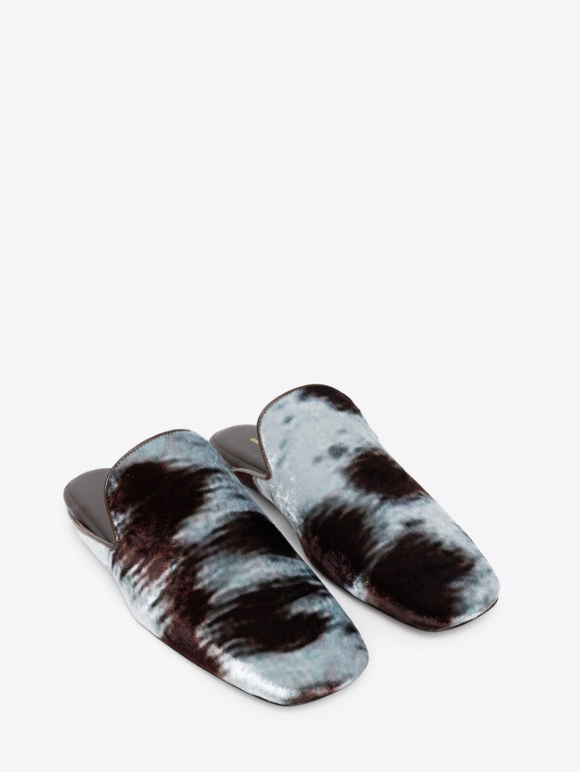 Pair of cowhide motif printed mules on a white background