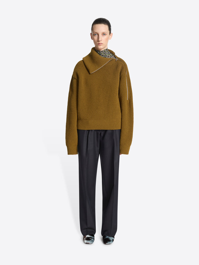 Model wearing a mustard colored sweater, black dress pants and a pair of cowhide motif printed mules on a white background