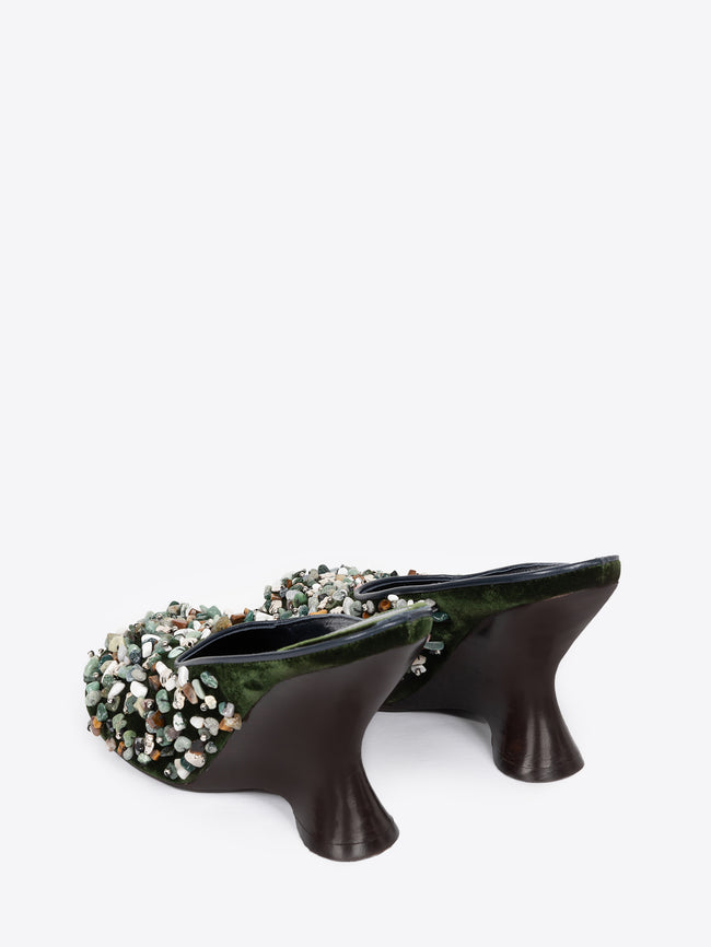 Backside of a pair of olive colored embellished mules on a white background