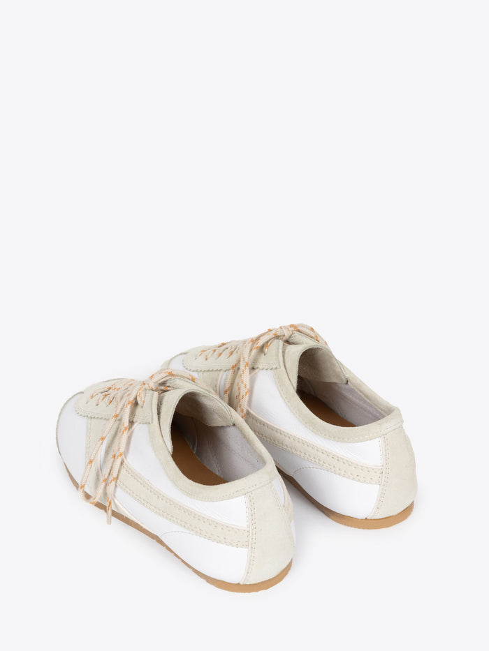 Backside of a pair of white, with beige accents, suede sneakers on a white background