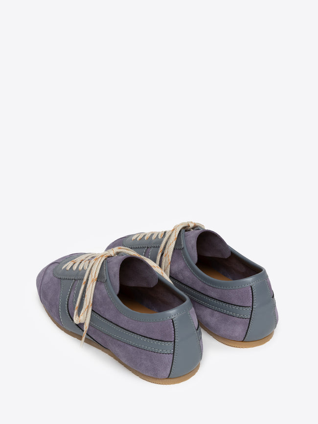 Backside of a pair of mauve suede sneakers on a white background