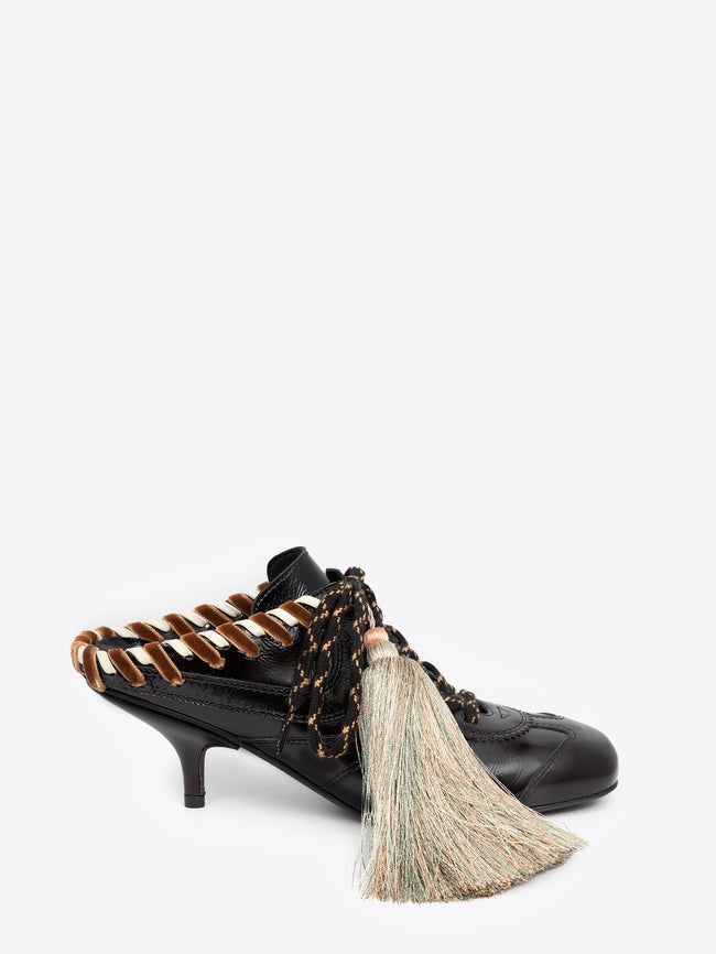 Black high-heeled shoe with brown accents and a decorative tassel on a white background