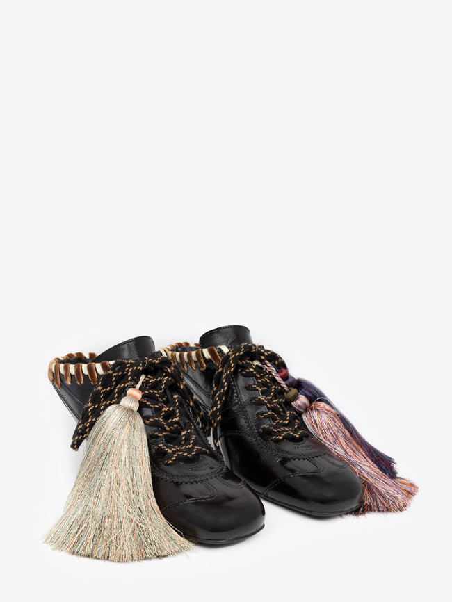 Black high-heeled shoe with brown accents and a decorative tassel on a white background