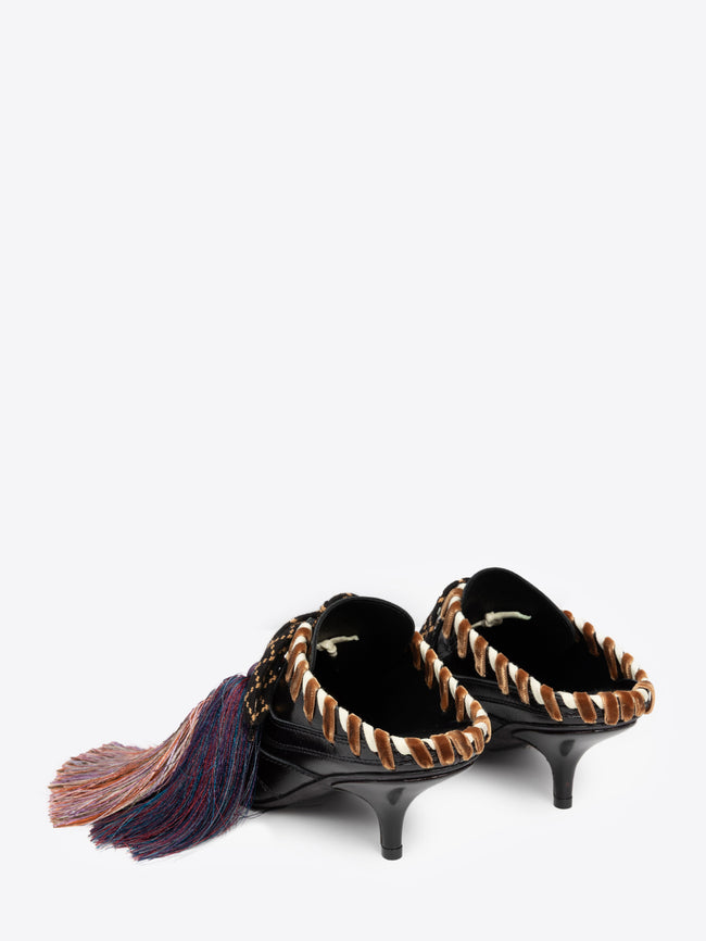Black high-heeled shoe with brown accents and a decorative tassel on a white background