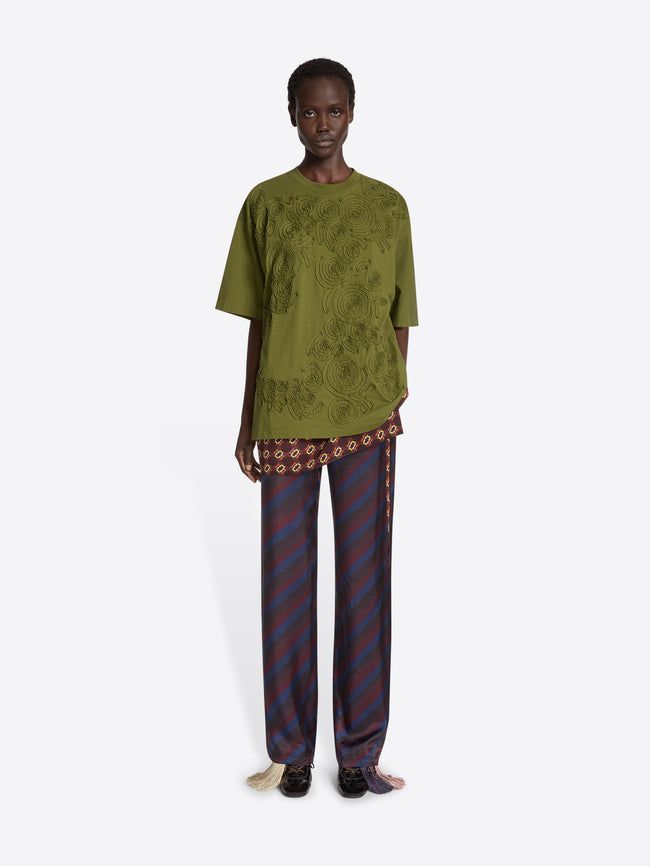 Person wearing a black high-heeled shoe with brown accents and a decorative tassel on a white background