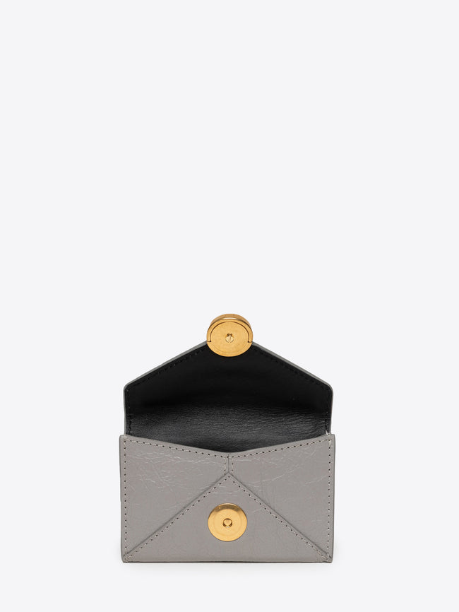 Close up of an opened light grey envelope-shaped cardholder with a gold clasp on a white background