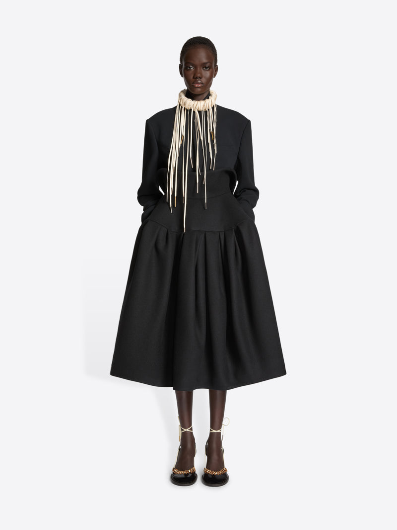 Person wearing a necklace with long hanging elements on a white background