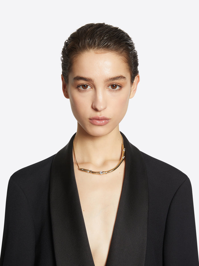 Person wearing a gold necklace with small pearls on a white background