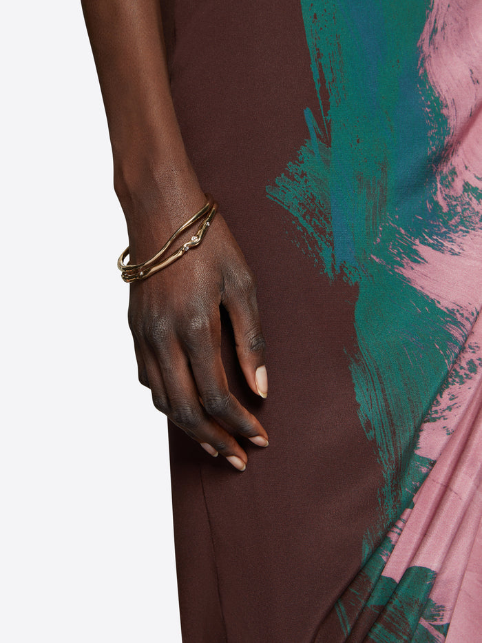 Person wearing a gold bracelet with small stones on a white background