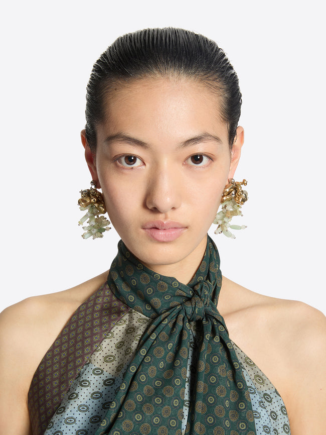 Woman wearing a patterned scarf and earrings on a white background