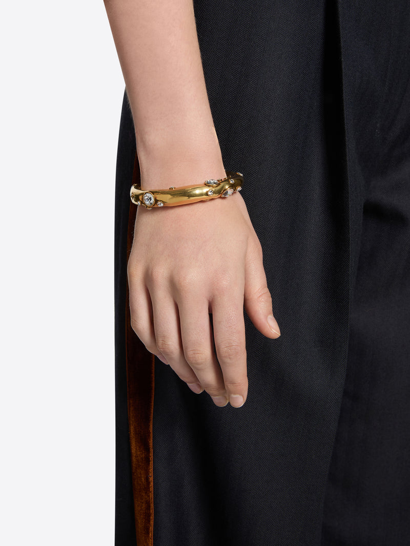 Gold bracelet on a person's wrist with a plain background
