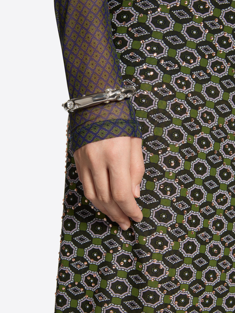 Close-up of a hand wearing a bracelet on a patterned fabric background