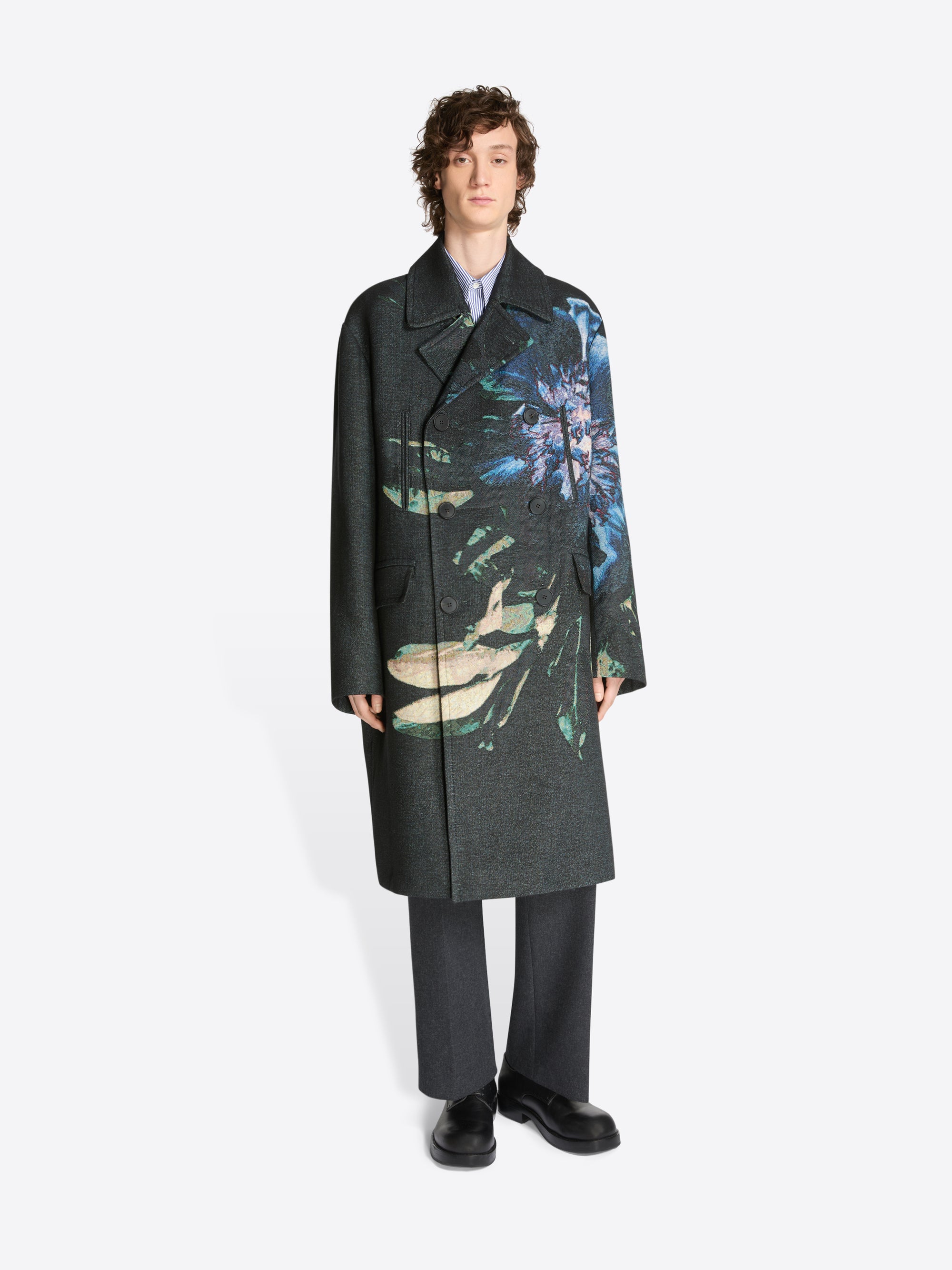 Model wearing dark grey pants, black boots and a black, floral patterned jacquard caban coat on a white background
