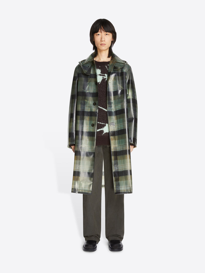 Person wearing a long plaid coat on a white background