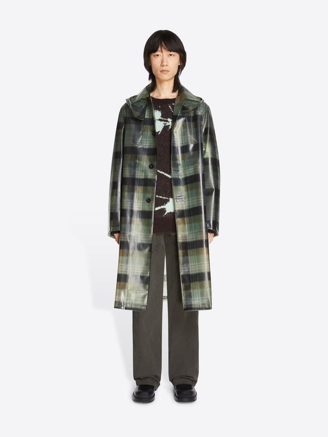 Person wearing a long plaid coat on a white background