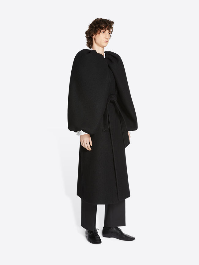 Person wearing a midnight colored, constructed wool coat on a white background
