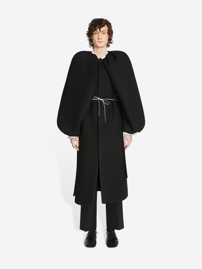 Person wearing a midnight colored, constructed wool coat on a white background