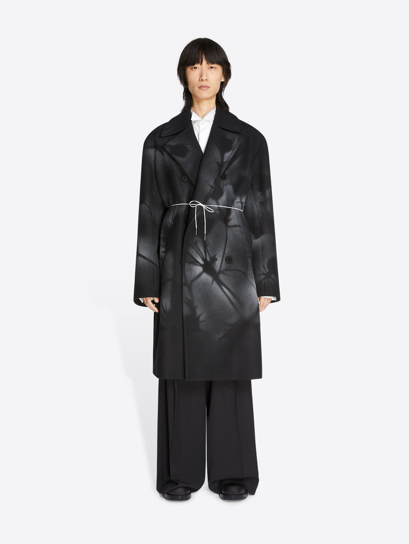 Person wearing a black coat and pants on a white background