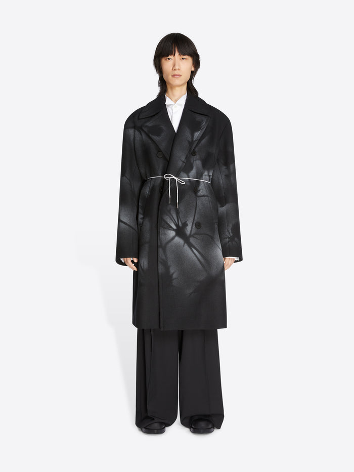 Person wearing a black coat and pants on a white background