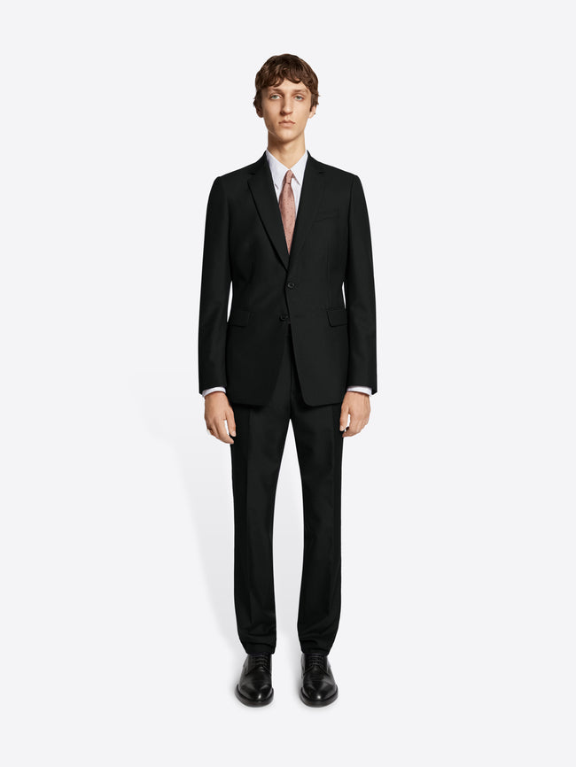 Person wearing black suit and black derby shoes on white background