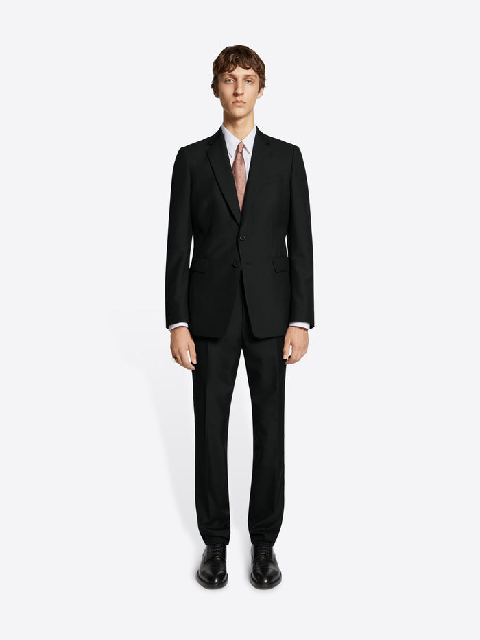 Person wearing black suit and black derby shoes on white background