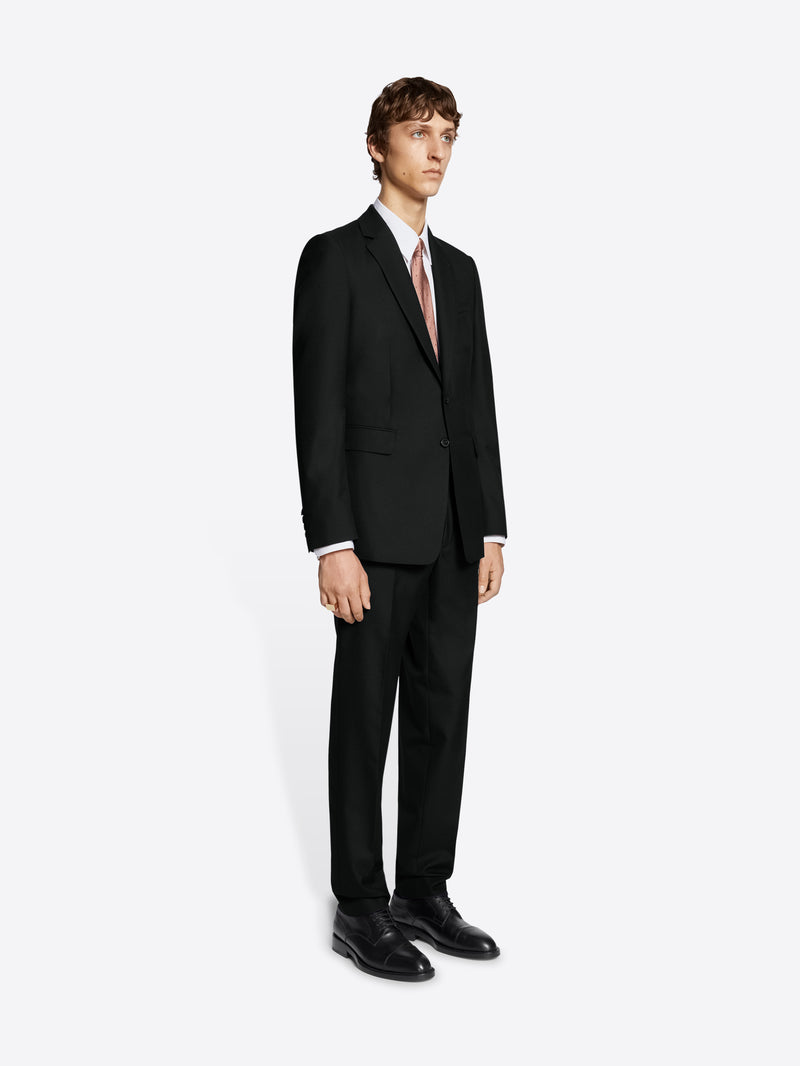 Person wearing black suit and black derby shoes on white background