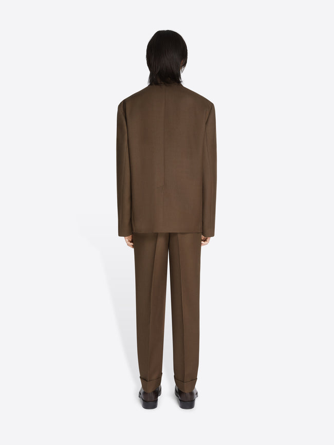 Backside of a model wearing a mud colored, boxy wool blazer and matching pants on a white background