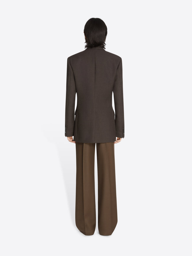 Backside of a model wearing a dark brown, regular fit wool blazer and lighter brown pants on a white background