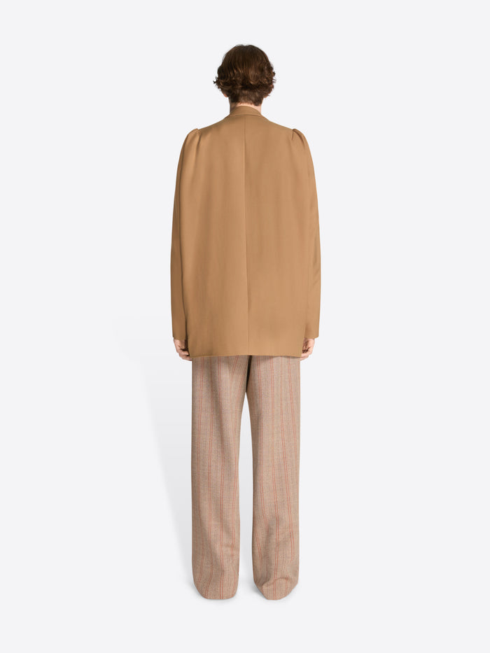 Person wearing a beige jacket and pants on a white background