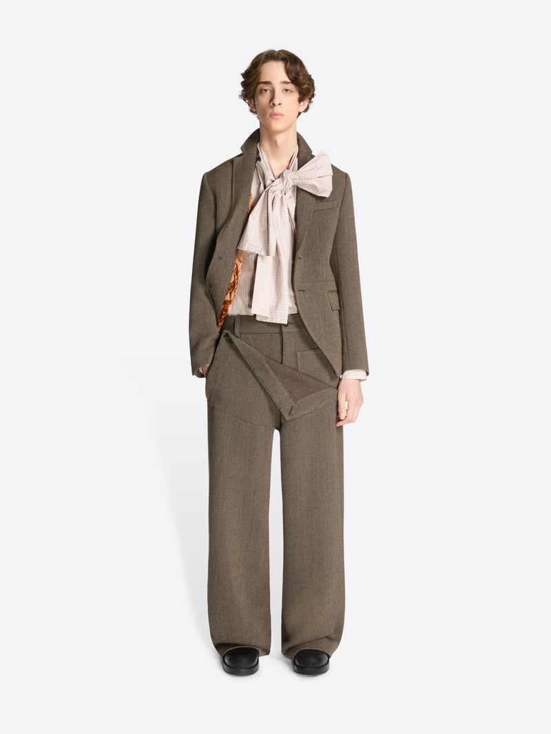 Model wearing a brown cropped suit jacket and matching pants on a white background