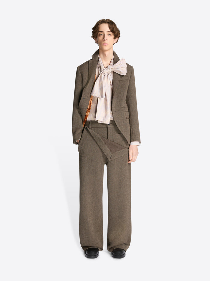 Model wearing a brown cropped suit jacket and matching pants on a white background
