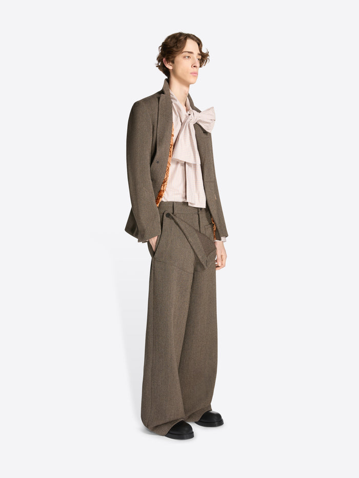 Model wearing a brown cropped suit jacket and matching pants on a white background