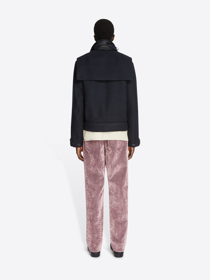 Backside of a person wearing a white shirt, midnight colored, short wool trench coat and pink pants on a white background