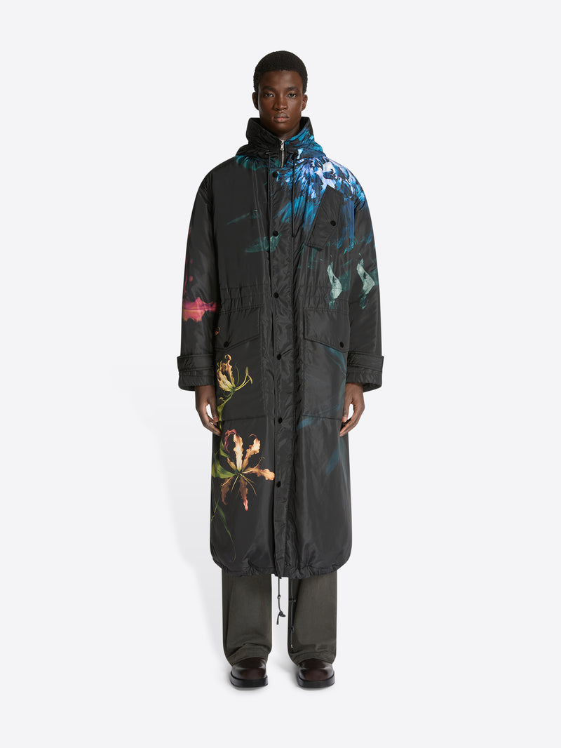 Person wearing a long, dark coat with colorful abstract patterns on a white background