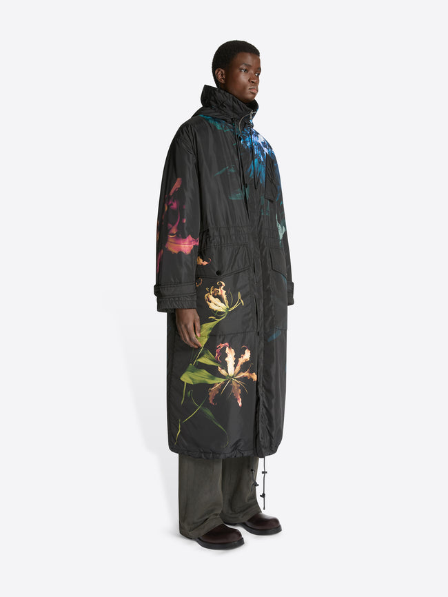 Person wearing a long, dark coat with colorful floral patterns on a white background