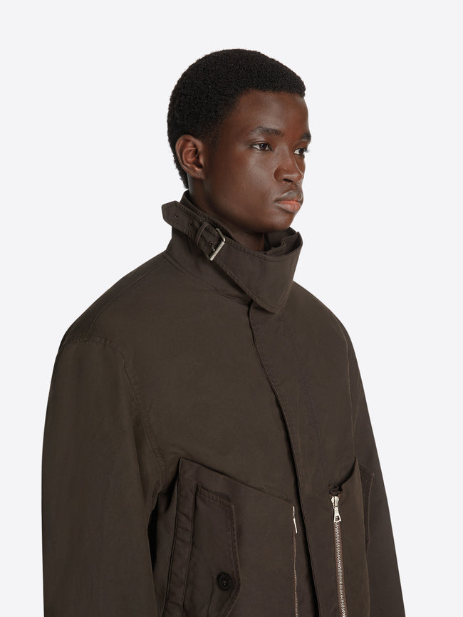 Clos-up of a model wearing a brown overdyed shell jacket on a white background