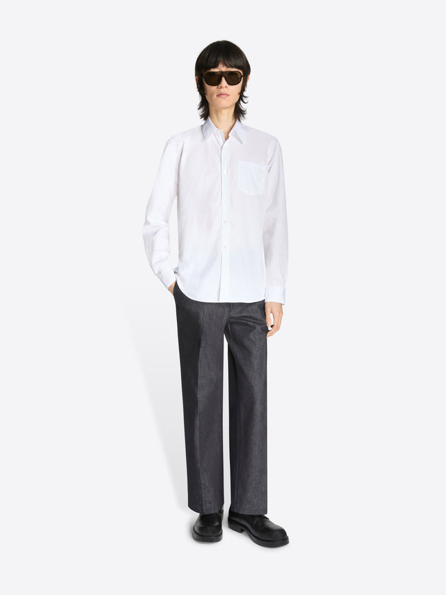 Person wearing a white shirt and dark pants on a white background
