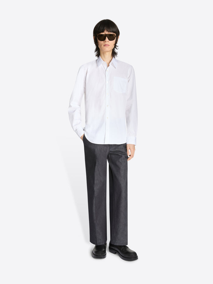 Person wearing a white shirt and dark pants on a white background