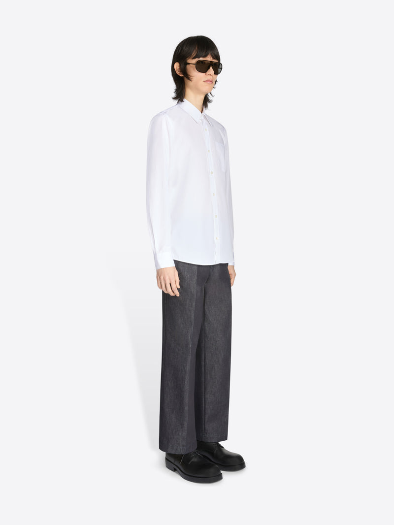 Person wearing a white shirt and dark pants on a white background