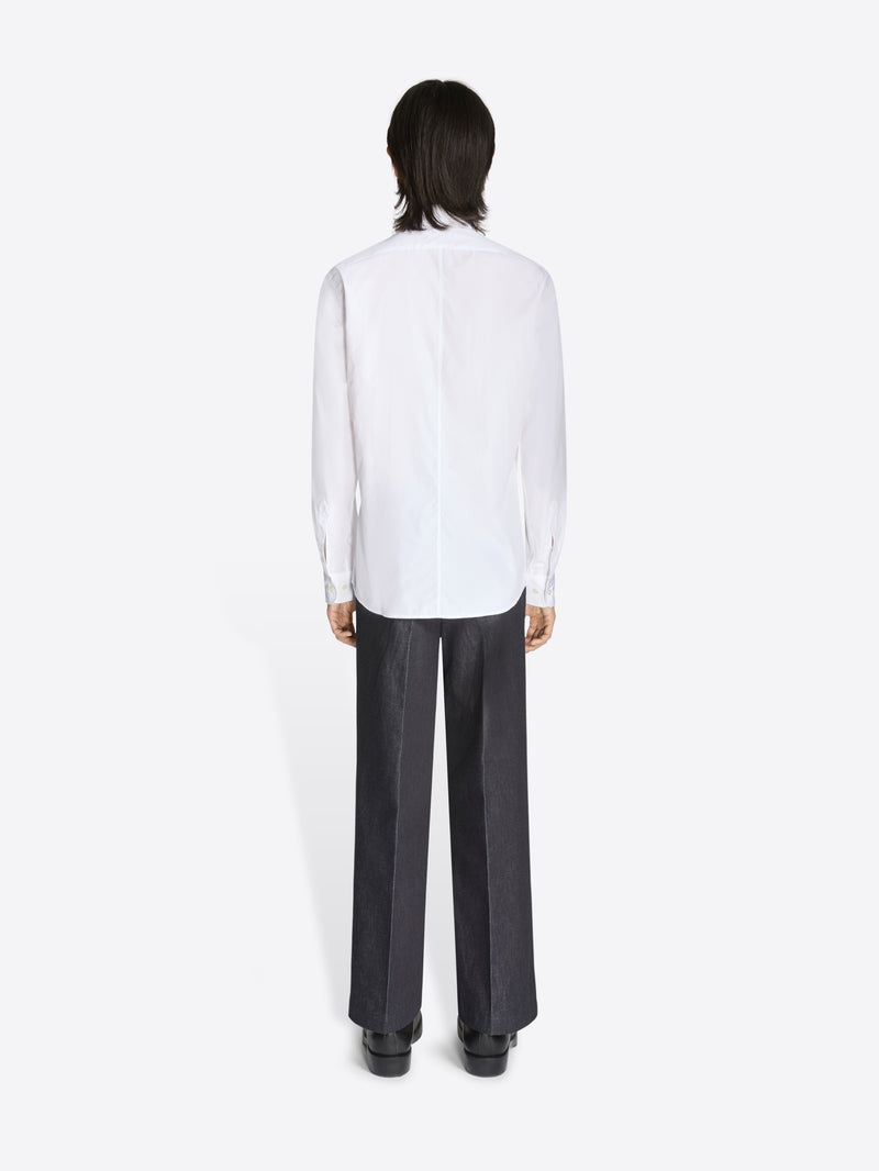 Person wearing a white shirt and black pants on a white background