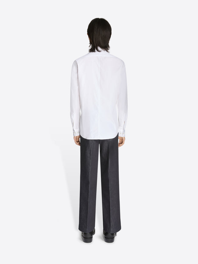 Person wearing a white shirt and black pants on a white background