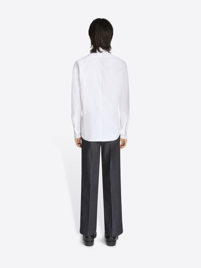Person wearing a white shirt and black pants on a white background
