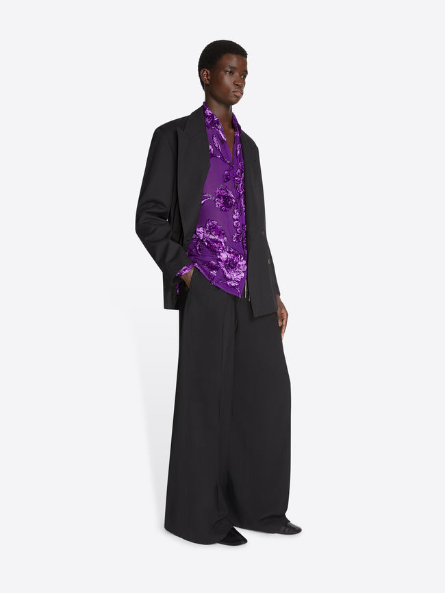 Model wearing a purple, sheer shirt, a black blazer shirt and black matching pants on a white background