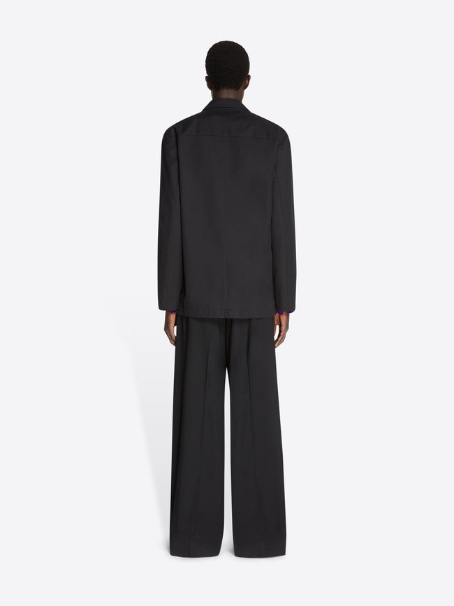 Backside of a model wearing a black blazer shirt and matching pants on a white background