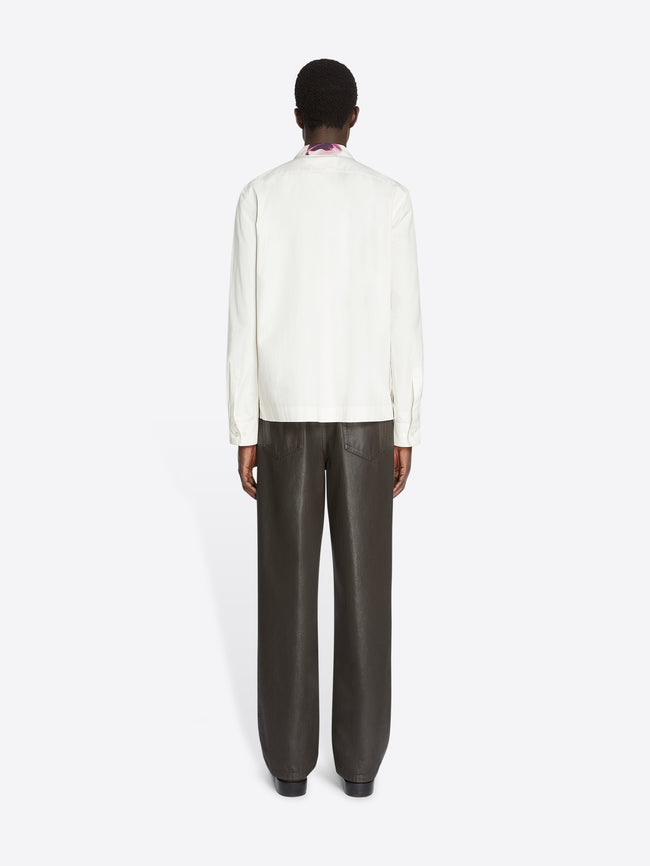 Backside of a model wearing a white cotton shirt and grey pants on a white background