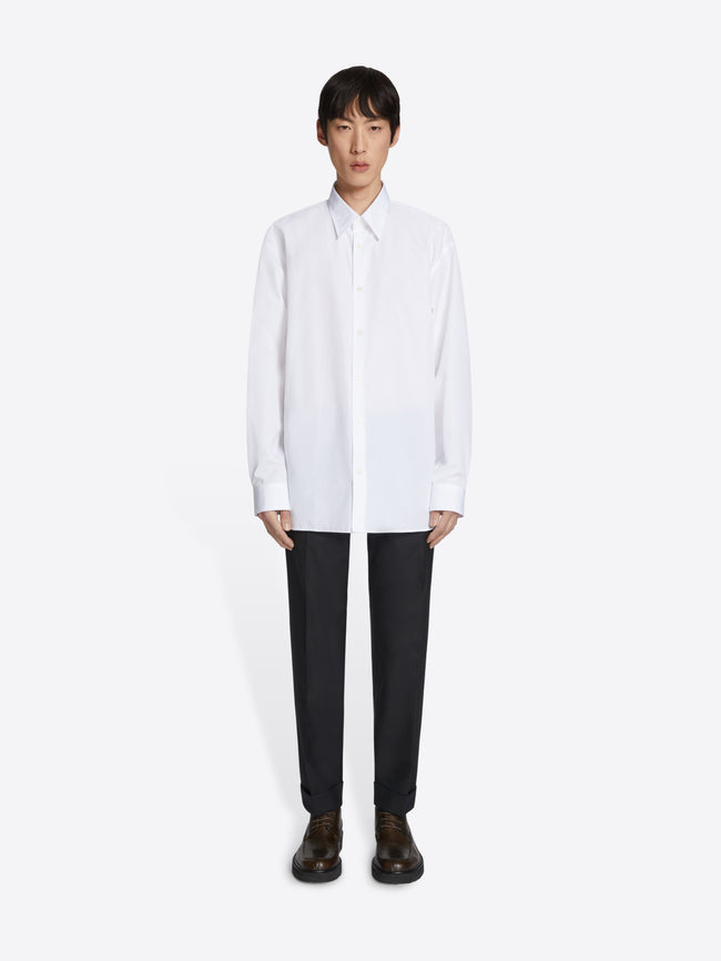 Person wearing a white shirt and black pants on a white background