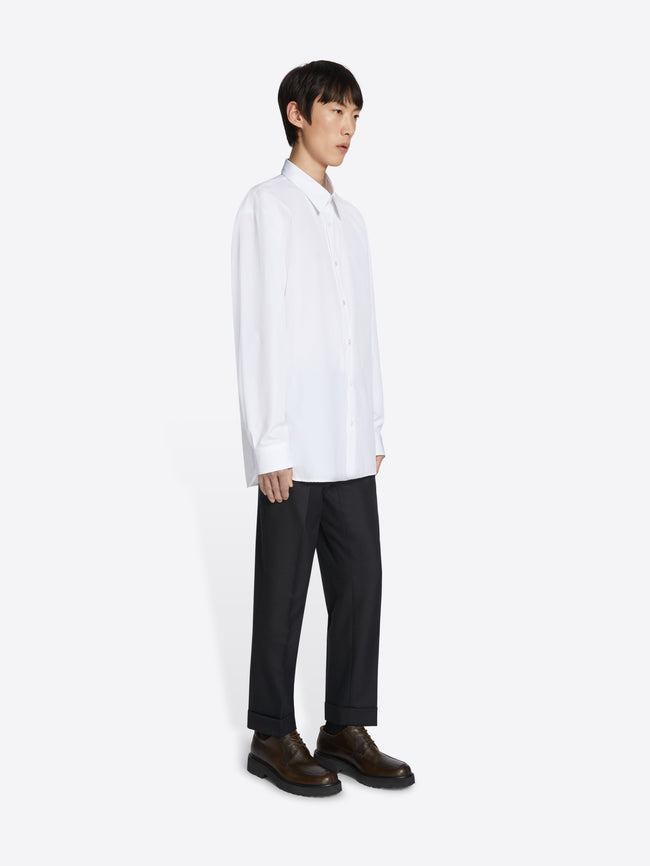 Person wearing a white shirt and black pants on a white background