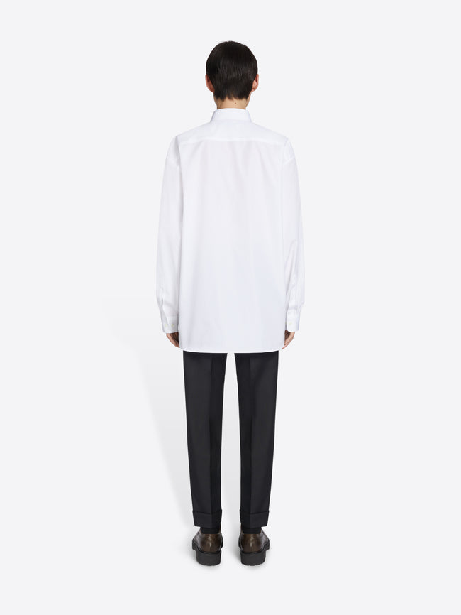 Person wearing a white shirt and black pants on a white background